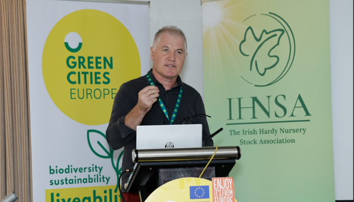 An image of the Guest Speaker standing behind a Podium giving a talk