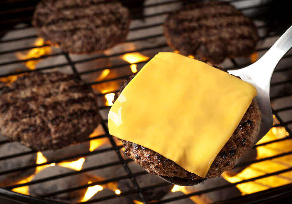 GoBia foodservices promo image, showing a burger cooking on a barbeque with cheese on it