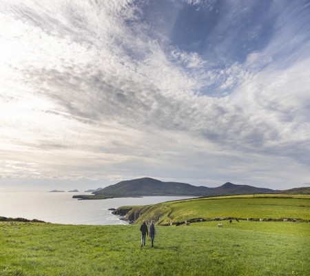 Landscape of the sea and cliffs with two farmers walking on a field