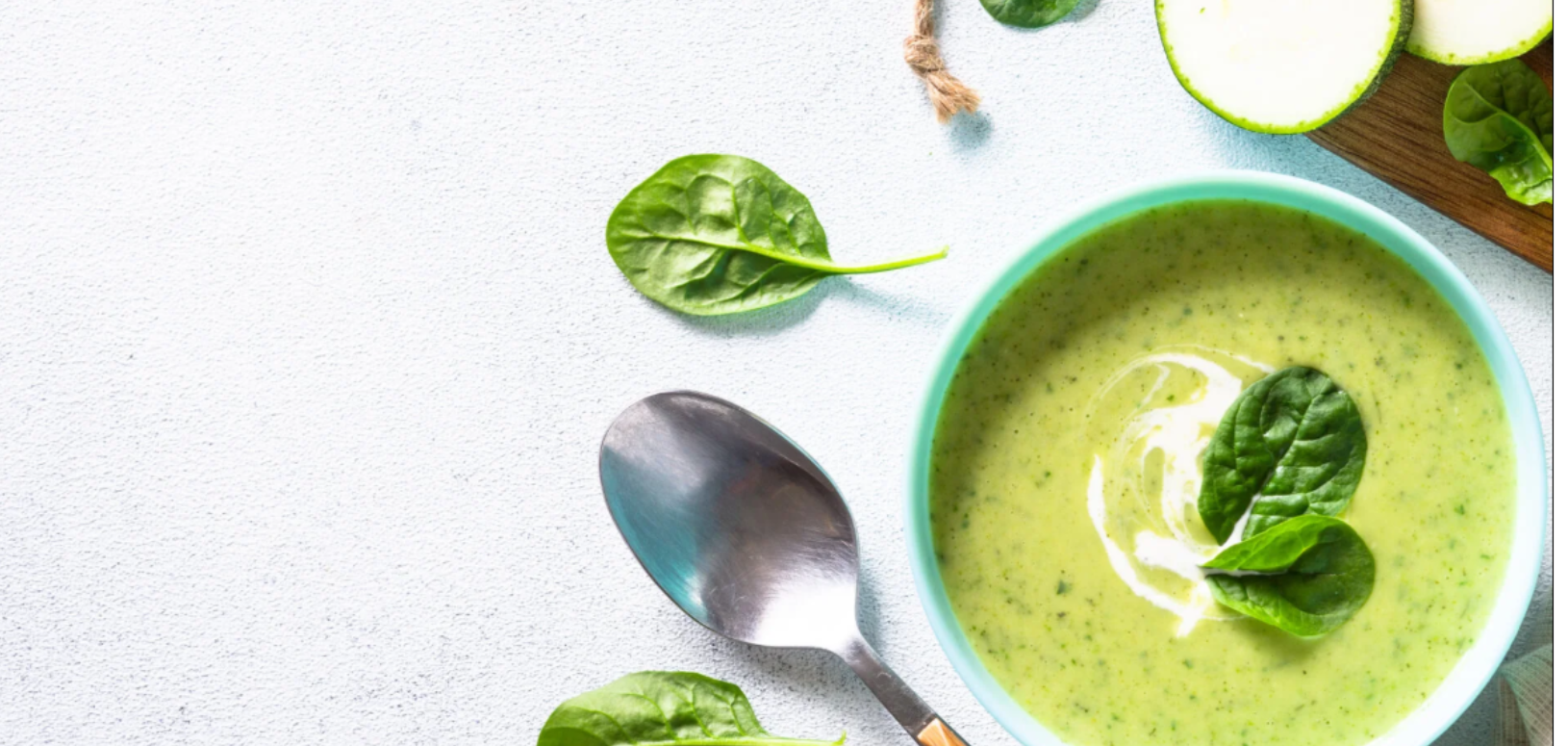Bowl of soup surrounded by garnish and a spoon