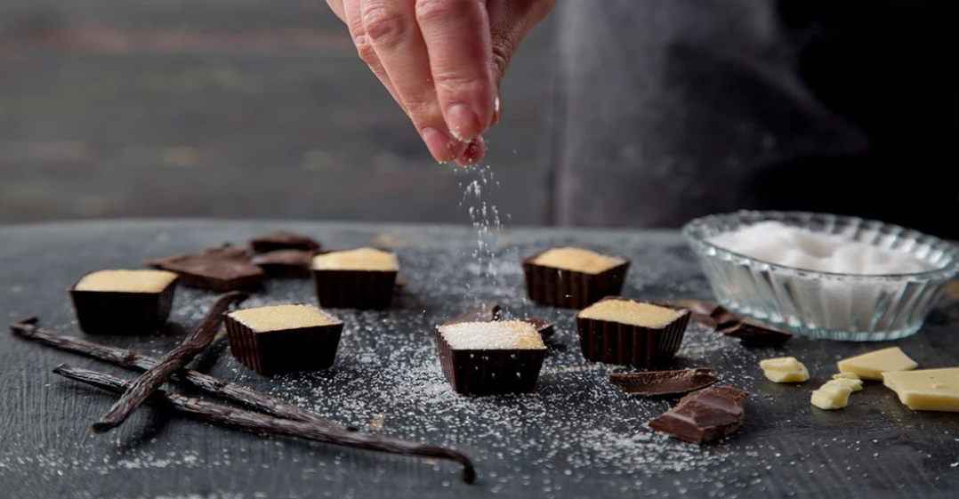 Hand sprinkling icing sugar over chocolate
